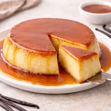 Portuguese vanilla flan sliced to reveal a smooth baked custard interior, with caramel sauce pooled along the plate