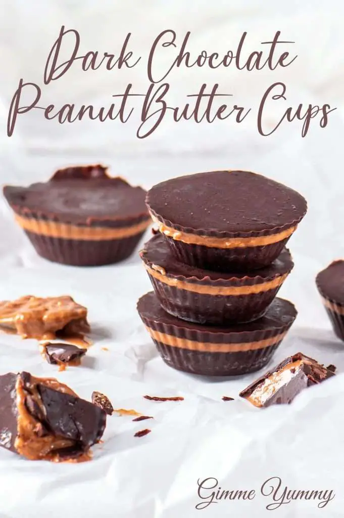 Homemade peanut butter cups surrounded by scattered chocolate pieces and creamy filling on white parchment.