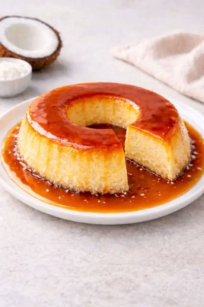 coconut flan with a slice removed showing creamy custard and caramel sauce