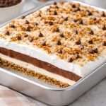 midnight cowboy delight layered chocolate pudding dessert in a baking dish topped with coconut pecans and chocolate chips