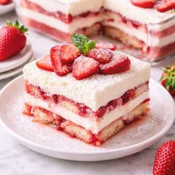 no-bake strawberry tiramisu in a glass dish topped with fresh strawberries and mascarpone cream
