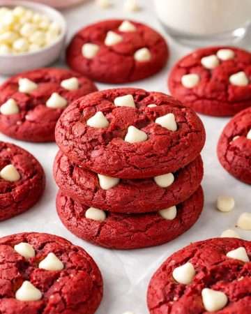 Stack of freshly baked red velvet cookies with white chocolate chips, soft and chewy texture, arranged on a table