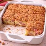 rhubarb coffee cake with cinnamon streusel topping in a baking dish with slices removed showing the moist crumb